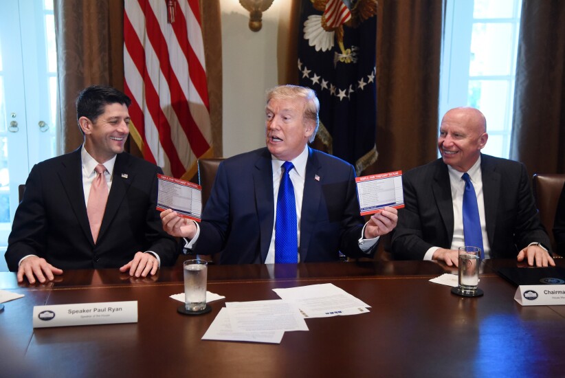 U.S. President Donald Trump, center, speaks while holding up "Simple, Fair, 'Postcard' Tax Filing" cards as U.S. House Speaker Paul Ryan, a Republican from Wisconsin, left, and Representative Kevin Brady, a Republican from Texas and chairman of the House Ways and Means Committee, react during a meeting in the Cabinet Room of the White House in Washington, D.C., U.S., on Thursday, Nov. 2, 2017. The House tax bill released Thursday preserves the carried interest tax break despite Trump and GOP leaders' promise to do away with loopholes for the wealthy.