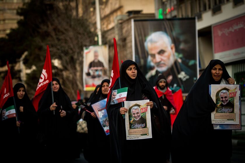 Mourners carry images of Iranian General Qassem Soleimani during the funeral ceremony in Tehran, Iran, on Monday.