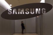 A woman waits for an elevator behind a Samsung Electronics Co. logo displayed at the company's Seocho office building in Seoul.