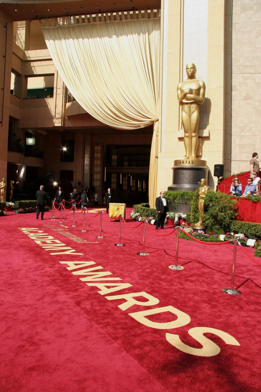 An Oscar statue stands next to the red carpet entrance to Academy Awards.