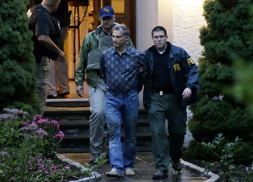 Vitaly Korchevsky is escorted in handcuffs from his home by agents from the Federal Bureau of Investigation (FBI) in Glen Mills, Pennsylvania, U.S., on Tuesday, Aug. 11, 2015. Korchevsky, 50, was one of several men arrested Tuesday morning in the biggest case of insider trading linked to the fast-growing threat of global cybercrime. The alleged scheme stretched from the affluent suburbs of Philadelphia, where Korchevsky ran the small investment firm NTS Capital Fund, to the darkest realms of the Internet.