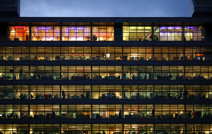 Electric lights illuminate office workers inside PwC's building in Dublin