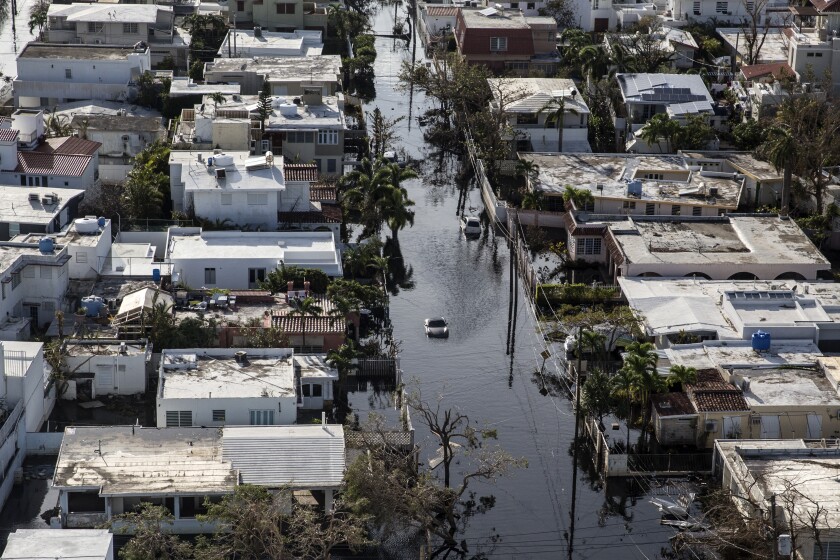 A vehicle drives through streets filled with floodwater and past destroyed homes caused by Hurricane Maria in this aerial photograph taken above Barrio Obrero in San Juan, Puerto Rico, on Monday, Sept. 25, 2017.