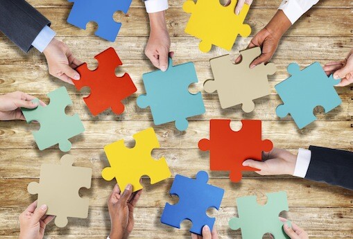 Group of Hands Holding Jigsaw Puzzle
