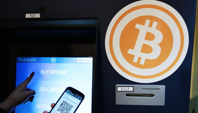 Eugene Aono, a spokesperson for BMEX bitcoin exchange, demonstrates usage of the company's Robocoin-branded automated teller machine (ATM) at The Pink Cow restaurant and bar in Tokyo.