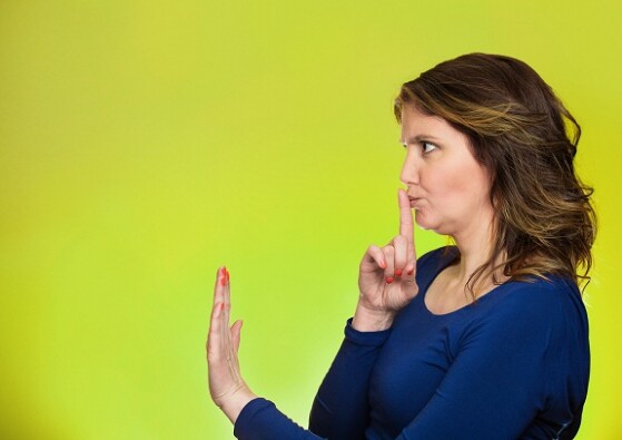 Closeup side view profile portrait serious woman finger, hand on lips, shhh gesture asking be quiet silence isolated green background. Negative facial expression sign emotion feelings, body language