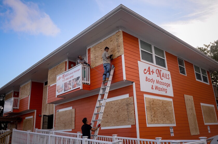 A worker stands on a ladder while securing plywood to windows ahead of Hurricane Florence in Carolina Beach, North Carolina, U.S., on Tuesday, Sept. 11, 2018. Hurricane Florence could be the most powerful storm to make landfall in North Carolina if predictions hold — no Category 4 hurricane has ever made landfall in the state. Photographer: Charles Mostoller/Bloomberg