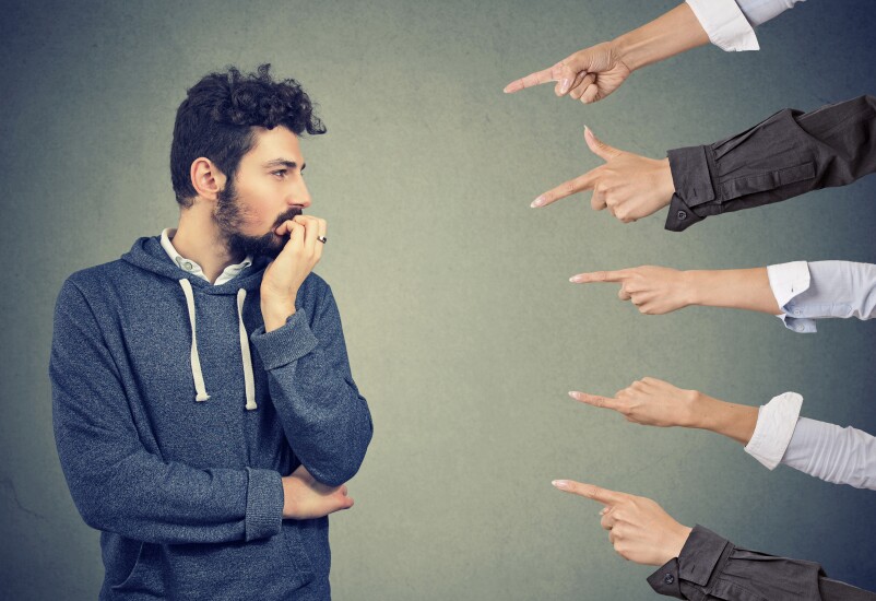 Anxious man judged by different people. Concept of accusation of guilty guy. Negative emotions face expression feeling