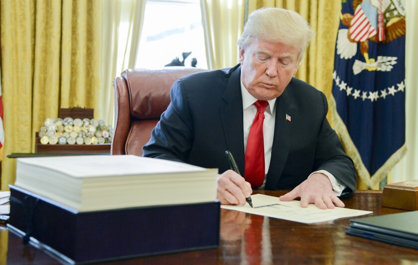 U.S. President Donald Trump signs a tax-overhaul bill into law in the Oval Office of the White House in Washington, D.C., U.S., on Friday, Dec. 22, 2017. This week House Republicans passed the most extensive rewrite of the U.S. tax code in more than 30 years, hours after the Senate passed the legislation, handing Trump his first major legislative victory providing a permanent tax cut for corporations and shorter-term relief for individuals. Photographer: Mike Theiler/Pool via Bloomberg