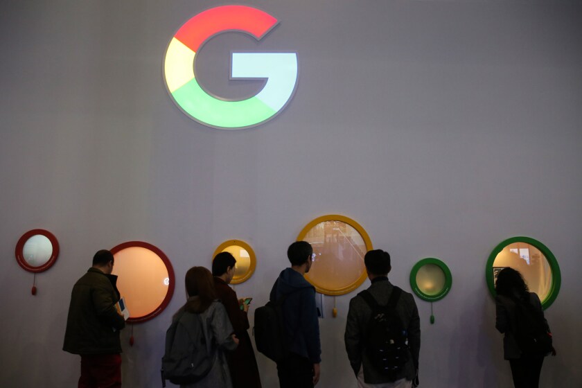 Attendees peer through portholes on the Google Inc. stand on the opening day of the MWC Barcelona in Barcelona, Spain.