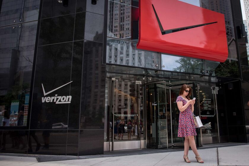 A pedestrian uses a smartphone outside a Verizon Communications Inc. store in downtown Chicago.