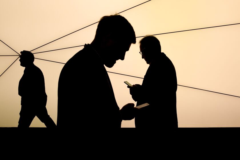 Attendees use mobile phones as they pass a Samsung Networks sign outside the Samsung Electronics Co. pavilion on the opening day of the MWC Barcelona in Barcelona, Spain, on Monday, Feb. 25, 2019. At the wireless industry’s biggest conference, over 100,000 people are set to see the latest innovations in smartphones, artificial intelligence devices and autonomous drones exhibited by more than 2,400 companies. Photographer: Angel Garcia/Bloomberg